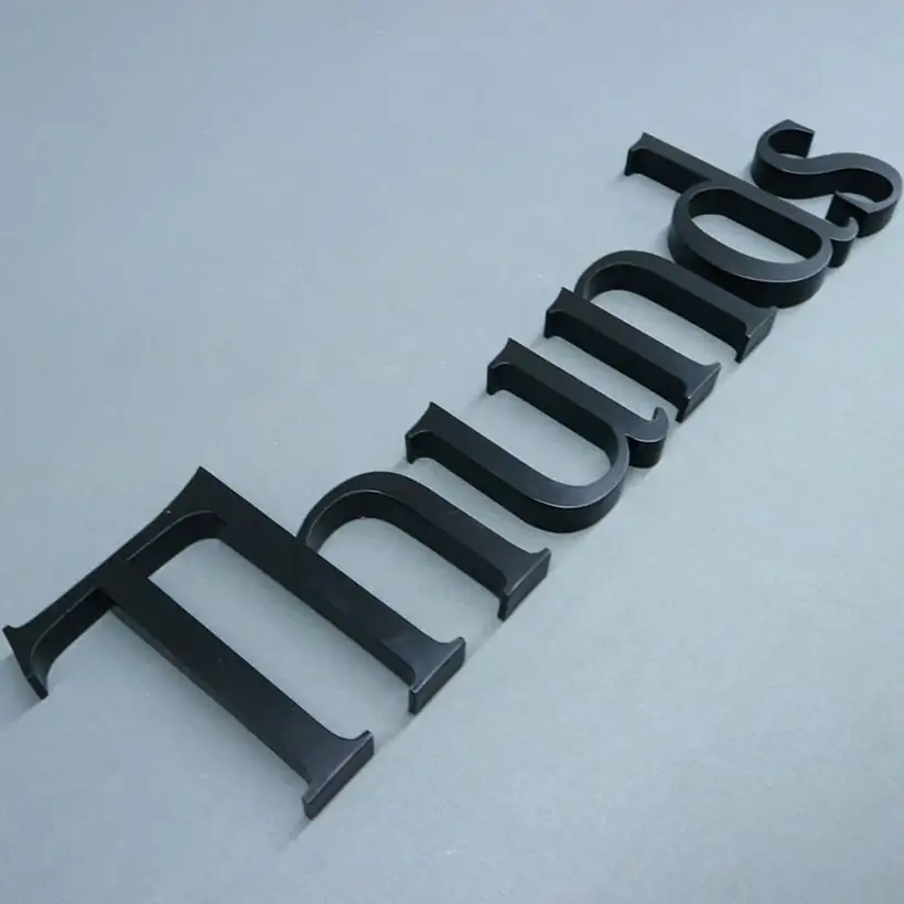 Matte black flat-cut solid letters laid out on a steel surface
